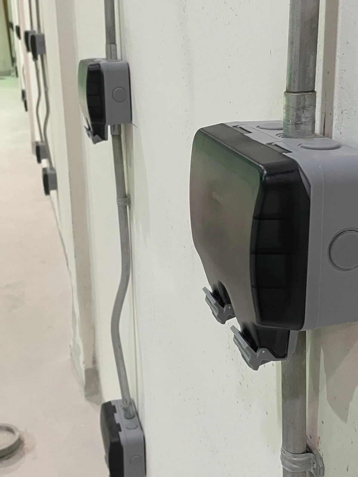 A row of covered electrical outlets connected by surface-mounted metal conduits